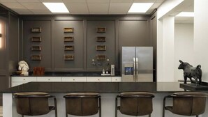 Una cocina moderna con una isla central, taburetes de bar y un refrigerador.