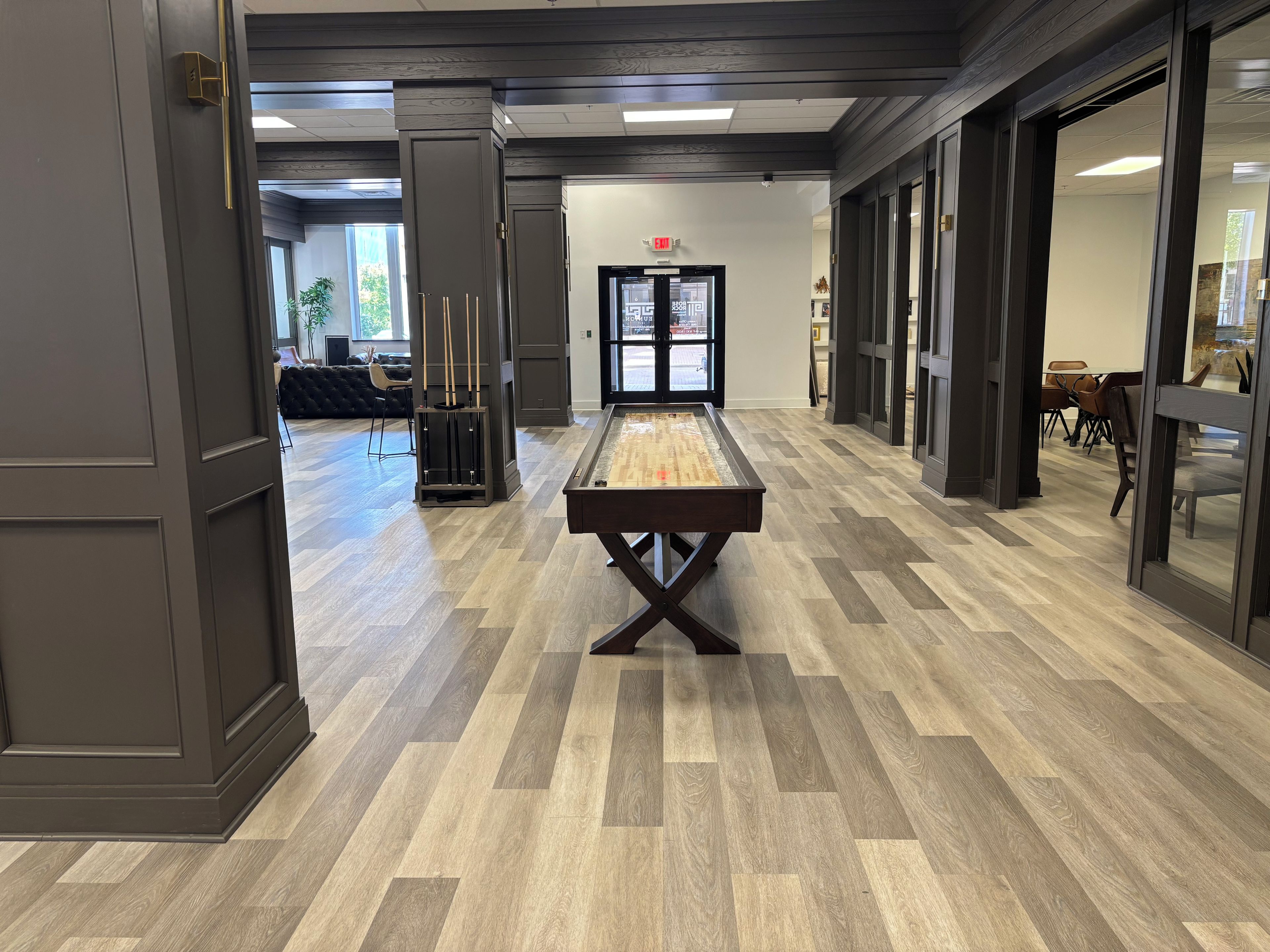 A billiards table in a hallway with wooden flooring and dark walls.