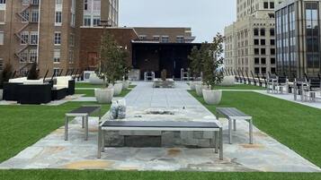A courtyard with outdoor seating, a central table, and two large planters.