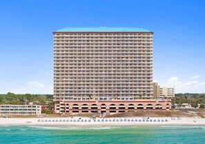 Ein Hochhaus-Hotel mit mehreren Balkonen, einer Strandlage und freiem Blick auf den Ozean.