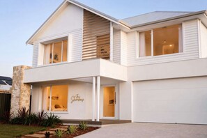Ein zweistöckiges Haus mit Garage, großen Fenstern und einer Wand aus Naturstein.