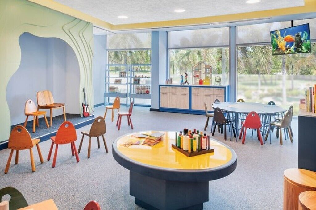 A children's playroom with a round table, chairs, and a television.