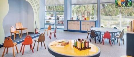 A children's playroom with a round table, chairs, and a television.