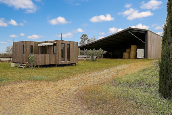 A modern building with a large open garage and a smaller wooden structure.