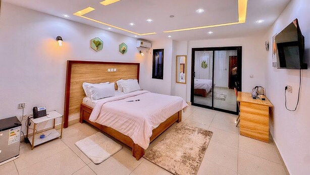 Un dormitorio moderno con cama, mesita de noche, escritorio y televisor.