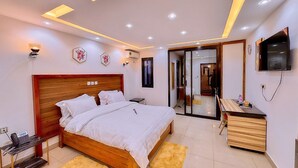Un dormitorio moderno con una cama de madera, mesitas de noche, un escritorio y un televisor.