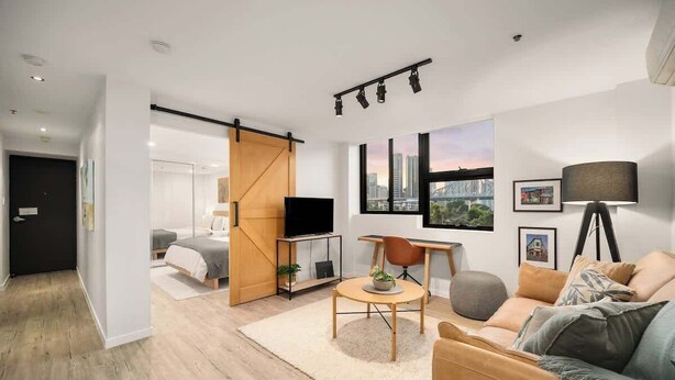 Una sala de estar moderna con un sofá, una mesa de centro, un televisor y vistas a la ciudad.