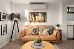 Ein modernes Wohnzimmer mit einer Couch, einer Stehlampe, einem Gemälde und einer Küchenzeile.