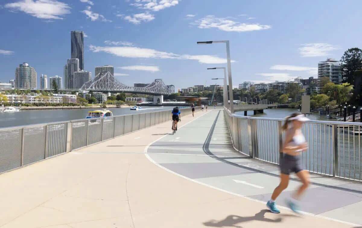 A pedestrian bridge with a city skyline in the background.
