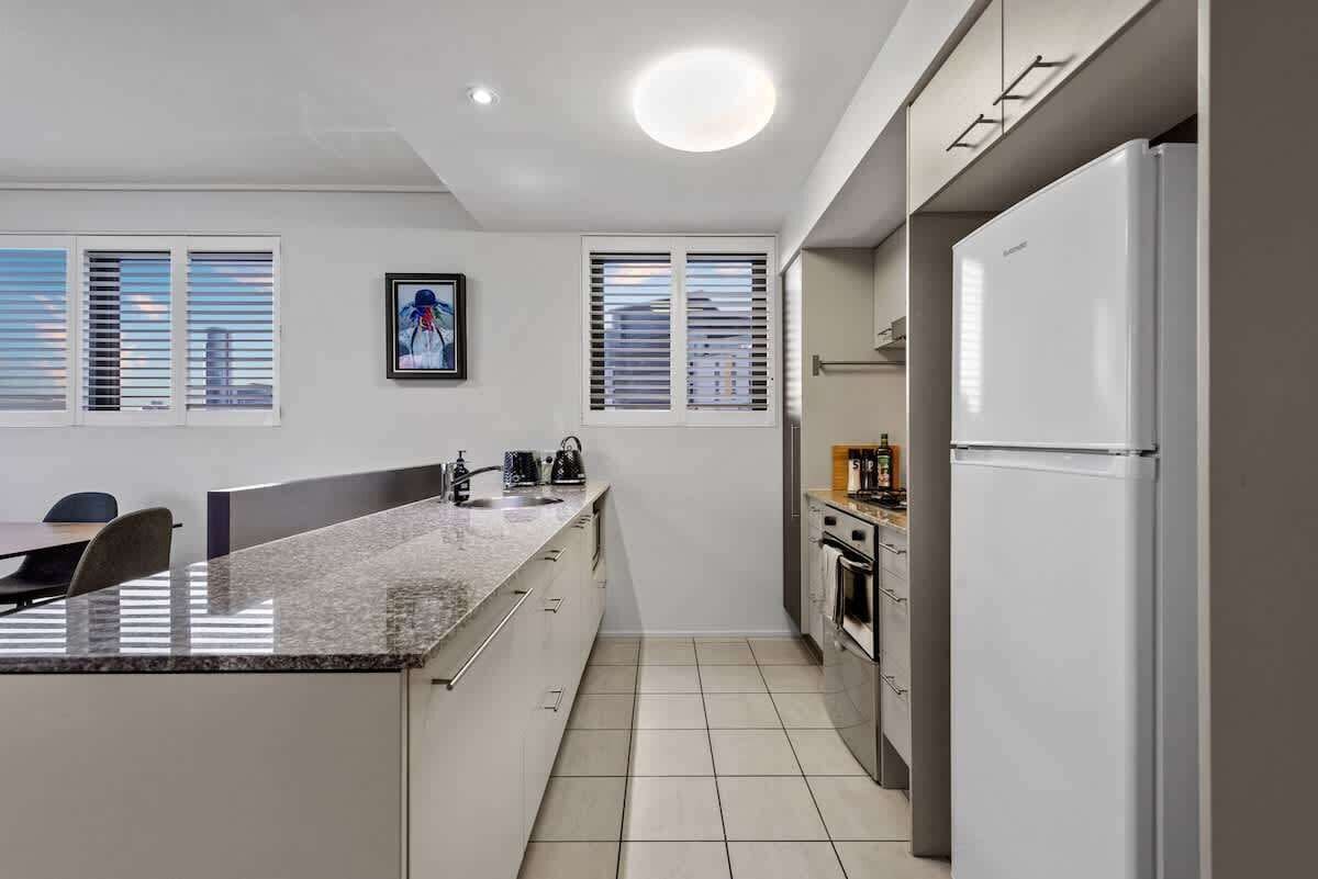 Una cocina moderna con una isla central, electrodomésticos de acero inoxidable y vistas de la ciudad a través de las ventanas.