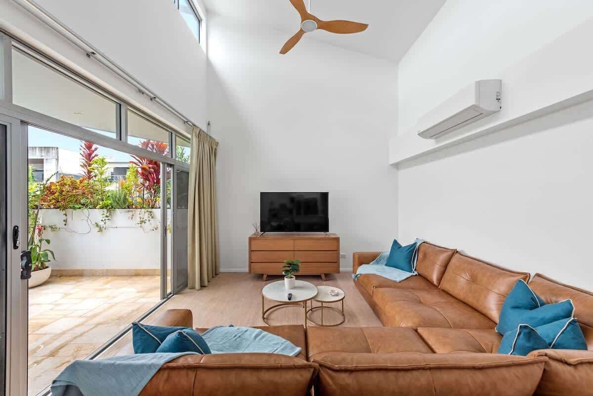 A modern living room with a sofa, TV, and a ceiling fan.