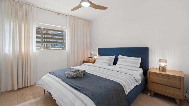 A bedroom with a bed, a nightstand, a ceiling fan, and a window with curtains. - Hidden Oasis 2bed-2bath-1car - 5 Mins to CBD (Brisbane)