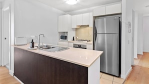 Uma cozinha moderna com ilha central, eletrodomésticos de aço inoxidável e armários brancos.