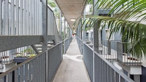 A corridor with metal railings, concrete flooring, and potted plants. - Central & Stylish! 1bed/1bath/1car ~ 5 Mins to CBD (Brisbane)