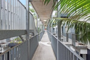 A corridor with metal railings, concrete flooring, and potted plants. - Central & Stylish! 1bed/1bath/1car ~ 5 Mins to CBD (Brisbane)
