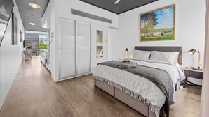 A bedroom with a bed, bedside tables, a ceiling fan, and a painting on the wall. - Central & Stylish! 1bed/1bath/1car ~ 5 Mins to CBD (Brisbane)