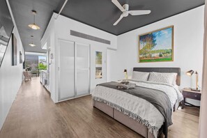 A bedroom with a bed, bedside tables, a ceiling fan, and a painting on the wall. - Central & Stylish! 1bed/1bath/1car ~ 5 Mins to CBD (Brisbane)