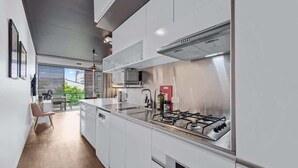 A modern kitchen with white cabinetry, a gas stove, and a view to an outdoor area. - Central & Stylish! 1bed/1bath/1car ~ 5 Mins to CBD (Brisbane)
