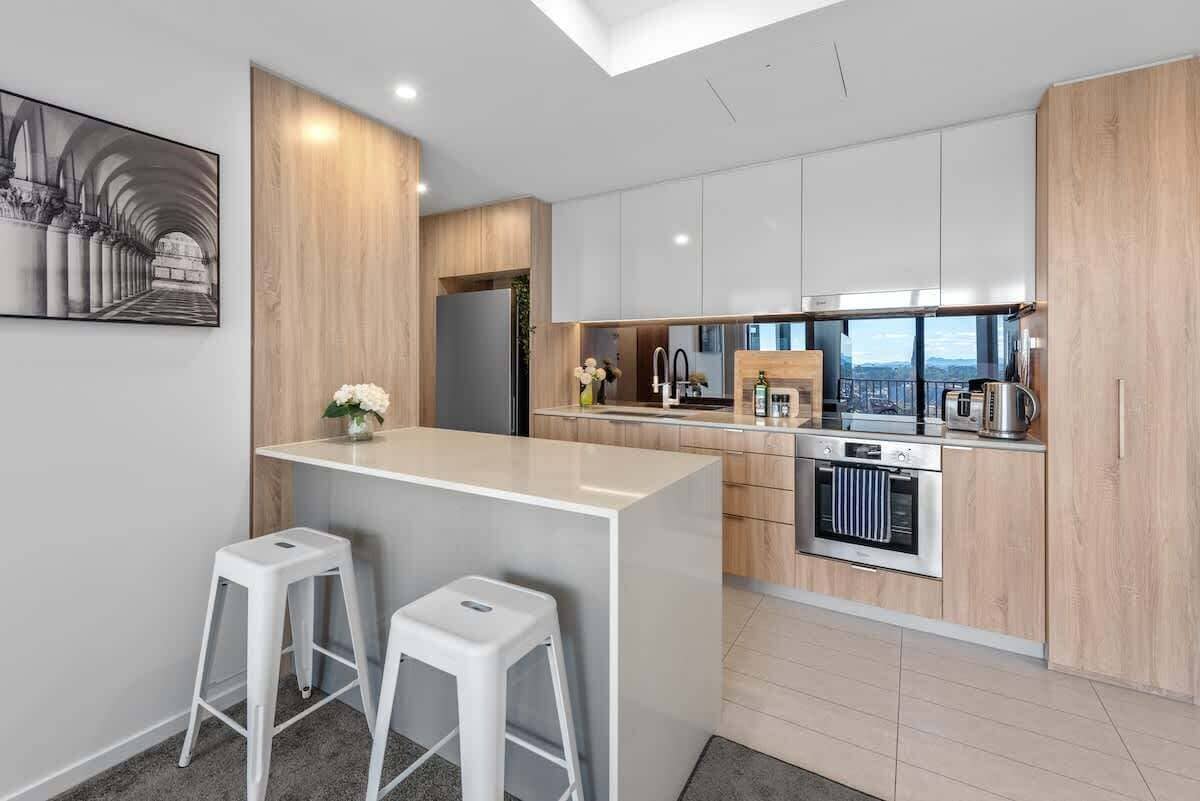 Una cocina moderna con una isla central, taburetes blancos y vistas a la ciudad.