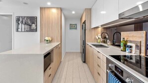 A modern kitchen with wooden cabinets, stainless steel appliances, and a central island. - City Living! 1bed/1bath/pool (Brisbane)