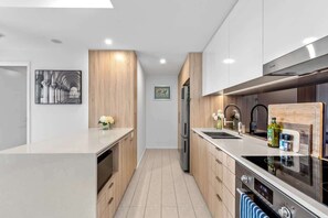 A modern kitchen with wooden cabinets, stainless steel appliances, and a central island. - City Living! 1bed/1bath/pool (Brisbane)