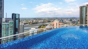 A rooftop infinity pool with a cityscape view, high-rise buildings, and a bridge in the background. - City Living! 1bed/1bath/pool (Brisbane)
