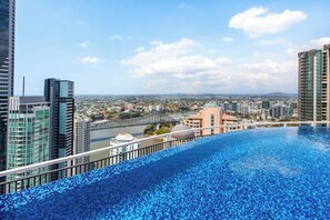 A rooftop infinity pool with a cityscape view, high-rise buildings, and a bridge in the background. - City Living! 1bed/1bath/pool (Brisbane)