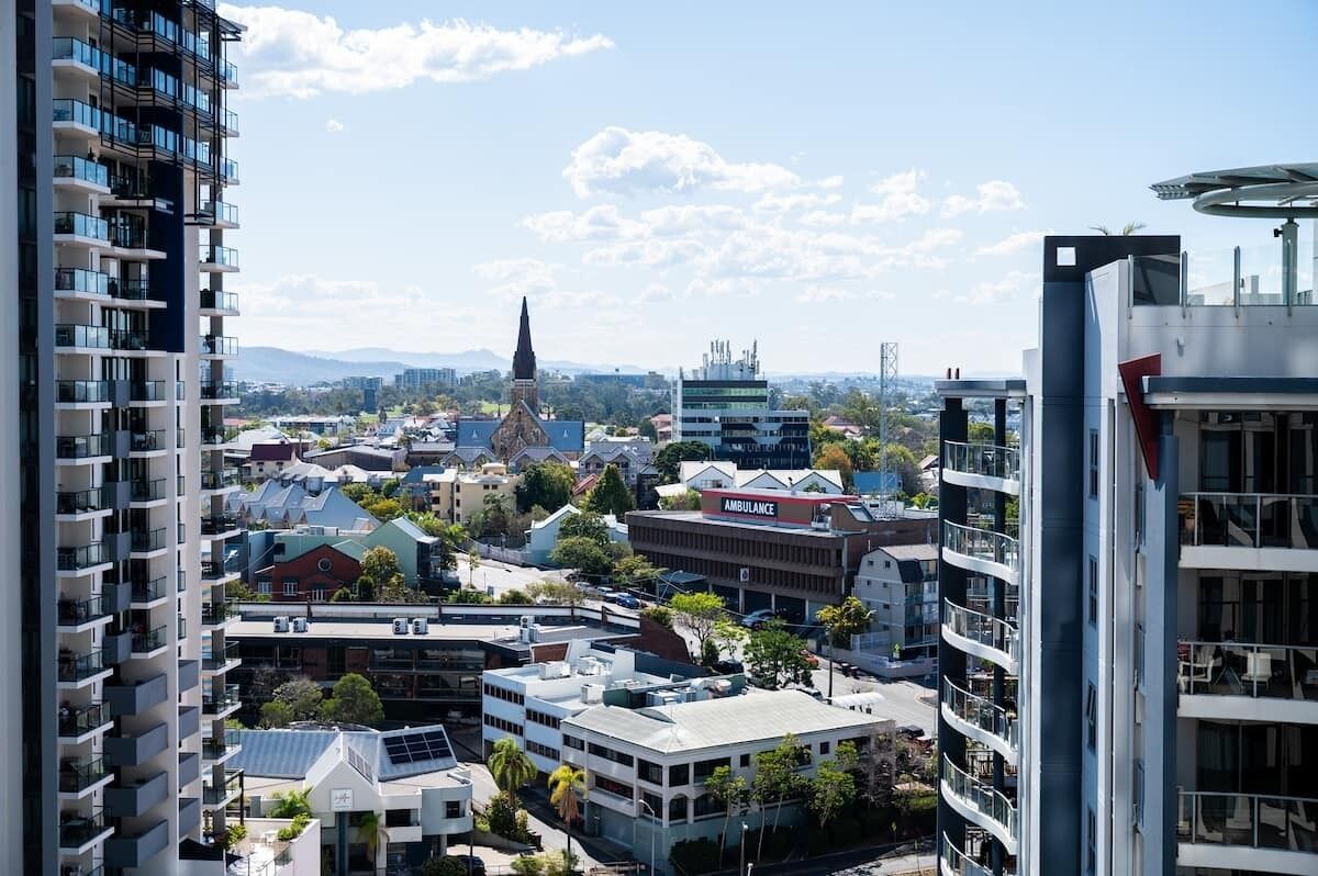 A high-rise building with multiple balconies, a prominent church spire, and a modern building with a solar panel.
