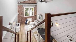 A modern loft with exposed brick, a staircase, a dining area, and a living room with a sofa and coffee table. - Woolstore Style! ~ 2bed/2bath/1car ~ Teneriffe (Brisbane)