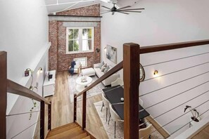 Ein modernes Loft mit freiliegenden Backsteinwänden, einer Treppe, einem Essbereich und einem Wohnzimmer mit Sofa und Couchtisch.