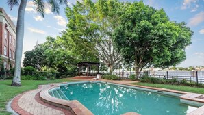 A swimming pool with a brick border, surrounded by trees and a gazebo. - Woolstore Style! ~ 2bed/2bath/1car ~ Teneriffe (Brisbane)