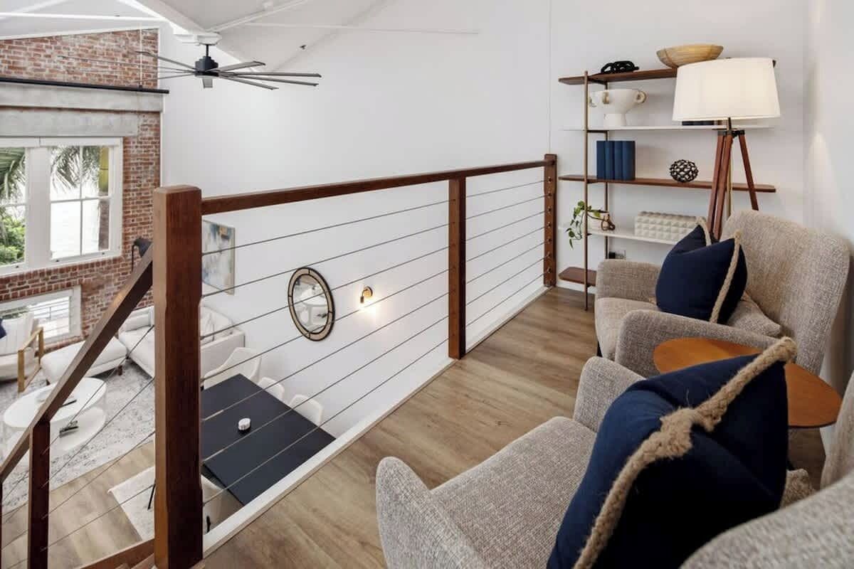 Una sala de estar moderna con una escalera de madera, un espejo redondo y una estantería.