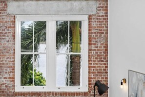 Ein Fenster mit Blick auf Palmen und eine Ziegelmauer.