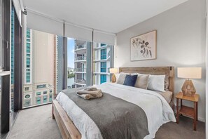Ein modernes Hotelzimmer mit einem großen Bett, Blick auf die Stadt und einem Balkon.