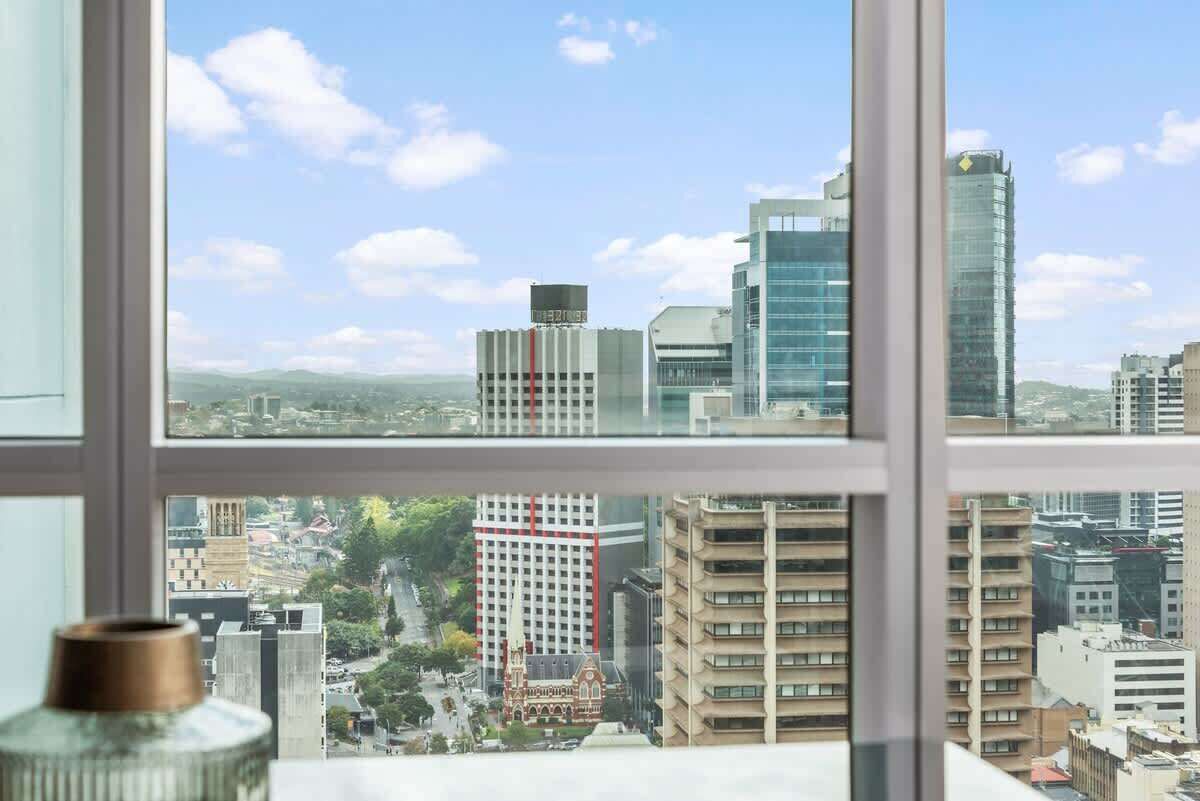 A cityscape through a window with modern buildings, a church, and a clear sky.