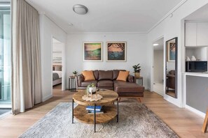 Ein modernes Wohnzimmer mit einem braunen Sofa, einem runden Couchtisch und zwei gerahmten Bildern an der Wand.