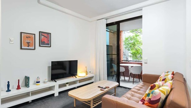 Ein modernes Wohnzimmer mit Fernseher, Sofa und Couchtisch.