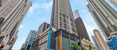 A tall urban building with a modern design, surrounded by other high-rise structures.