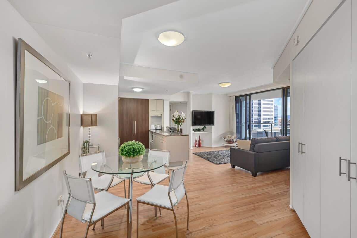 Un apartamento moderno con comedor, cocina, sala de estar y un gran ventanal con vistas a la ciudad.