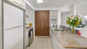 A modern kitchen with white appliances, a wooden cabinet, and a granite countertop. - Inner-city Vibes! 2bed/1bath/1car/balcony~cbd (Brisbane)