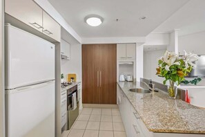 Eine moderne Küche mit weißen Geräten, einem Holzschrank und einer Arbeitsplatte aus Granit.