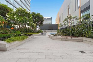 Ein Innenhof mit Pool, Sitzbereichen und modernen Gebäuden im Hintergrund.