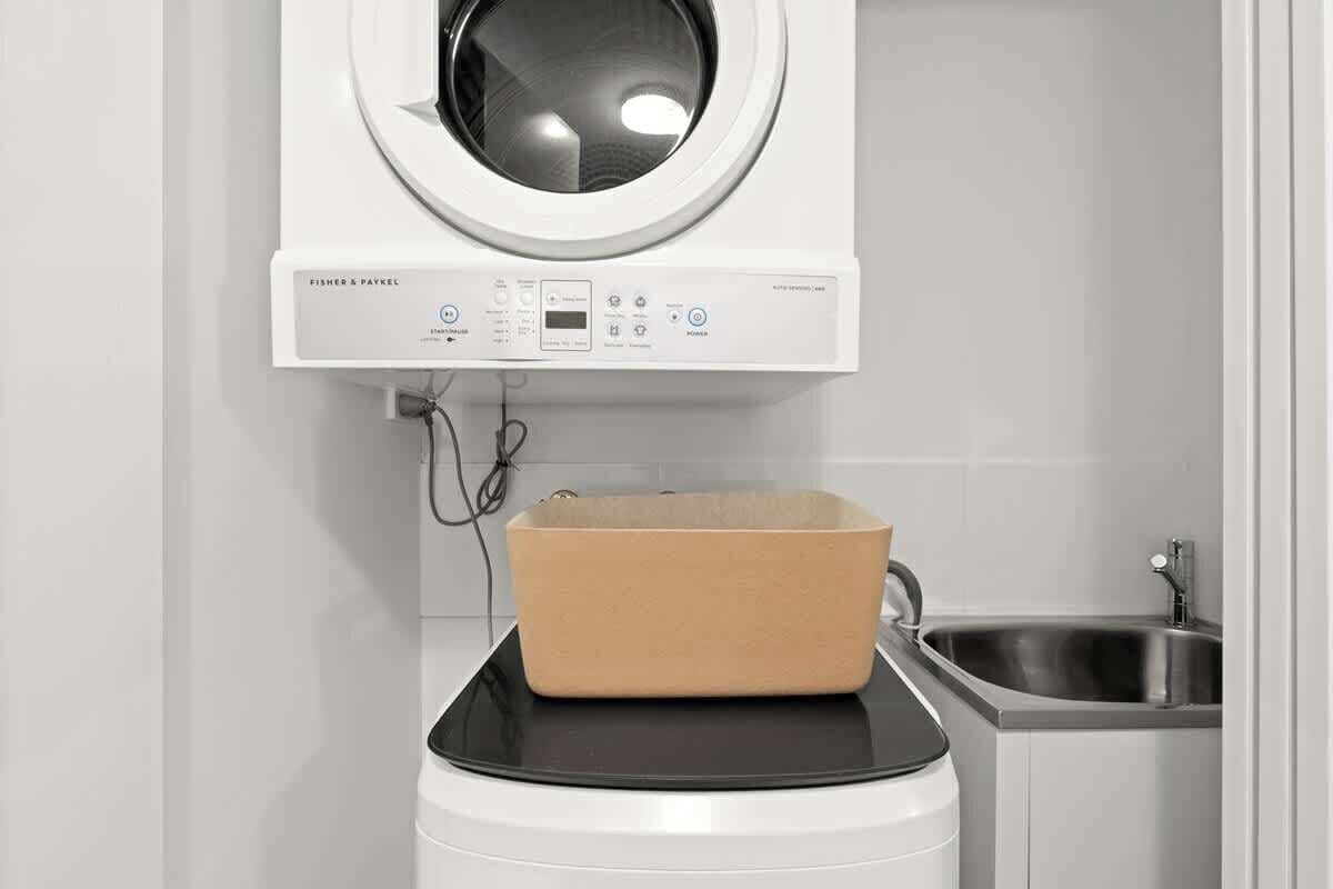 A laundry machine with a control panel and a beige laundry basket on top.