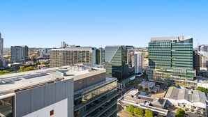 Eine Stadtansicht mit modernen Gebäuden, darunter ein markantes dreieckiges Bauwerk und ein großes Glasgebäude.