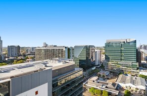 Eine Stadtansicht mit modernen Gebäuden, darunter ein markantes dreieckiges Bauwerk und ein großes Glasgebäude.