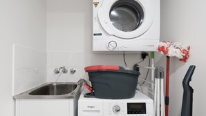A compact laundry area with a front-loading washer and dryer, a sink, and a mop. - The Executive! 1bed, 1bath, 1car, Views ~ CBD (Brisbane)