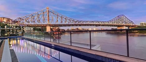 A swimming pool with a view of a bridge and buildings in the background.