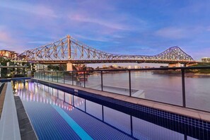 Une piscine avec vue sur un pont et des bâtiments en arrière-plan.