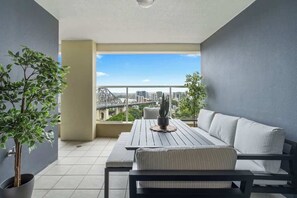 Ein Balkon mit Tisch, Sofa, Blumentöpfen und Blick auf die Stadt.
