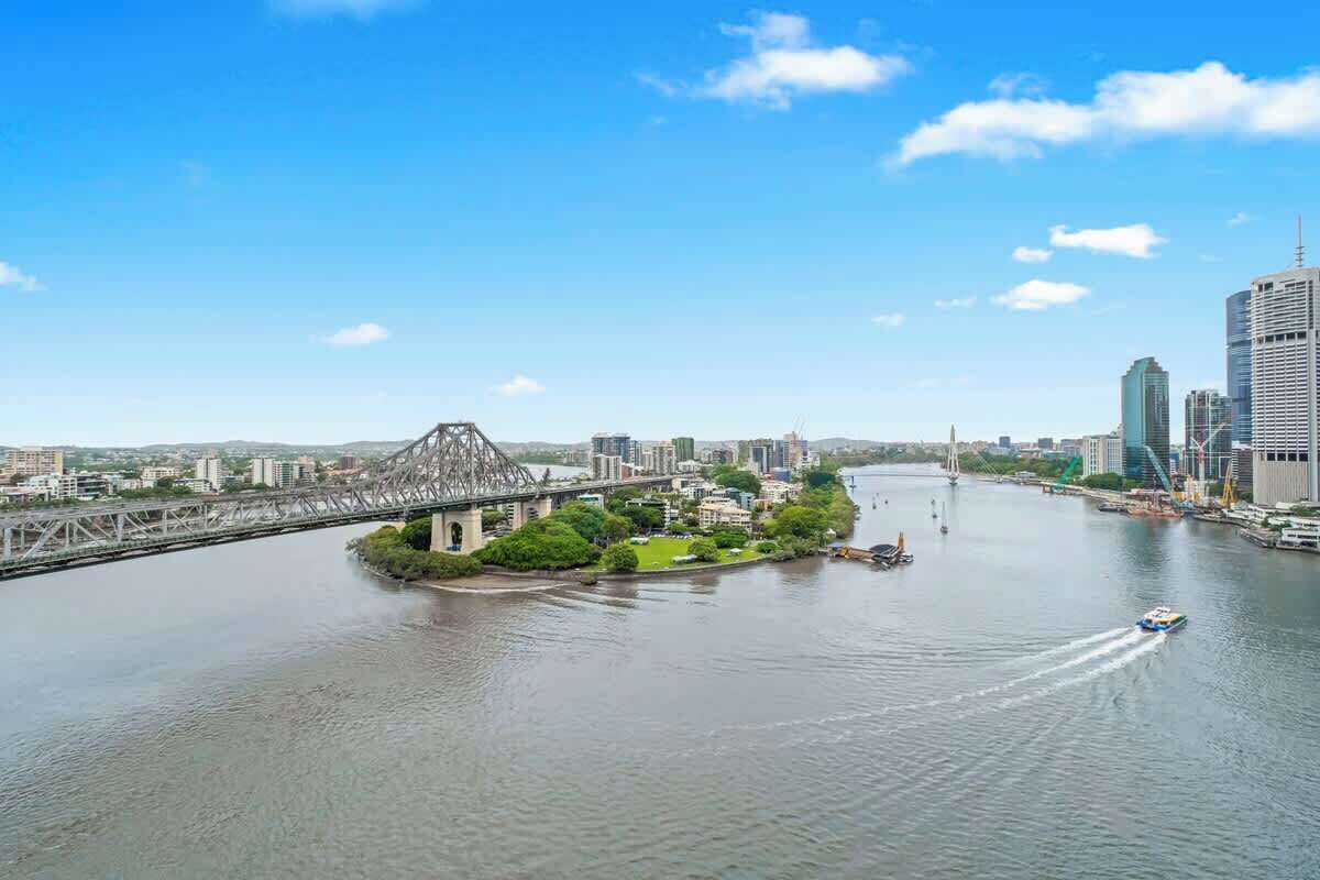 Une rivière traversée par un pont, une petite île verdoyante et une vue sur la ville avec ses gratte-ciel.
